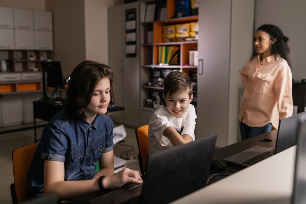 Students using laptops in a classroom with a teacher